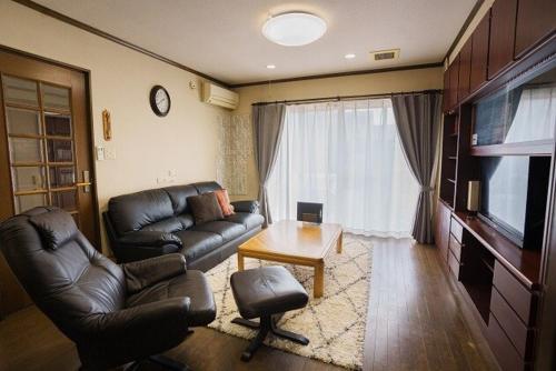 a living room with a leather couch and a television at 一棟貸切最大11名仲間と家族と恋人と心ゆくまで楽しむプライベートステイパーティーにも in Kakamigahara