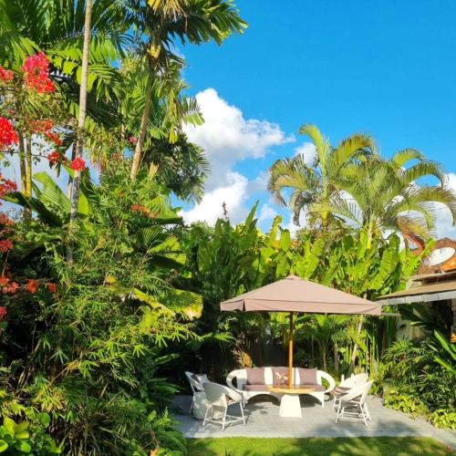 a patio with an umbrella and chairs and trees at Villa Casa Jamika in Seminyak