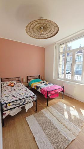 two beds in a room with a large window at l'Eclat Malouin - Parking & Garden in Dunkerque