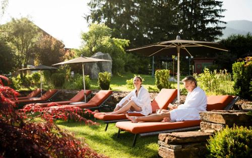 a group of people sitting on chairs in a garden at Mirabell Dolomites Hotel - Luxury Ayurveda & Spa in Valdaora