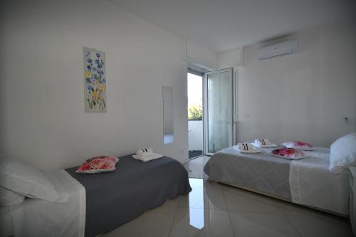 zwei Betten in einem weißen Zimmer mit Fenster in der Unterkunft Casa Solari Rapallo in Rapallo