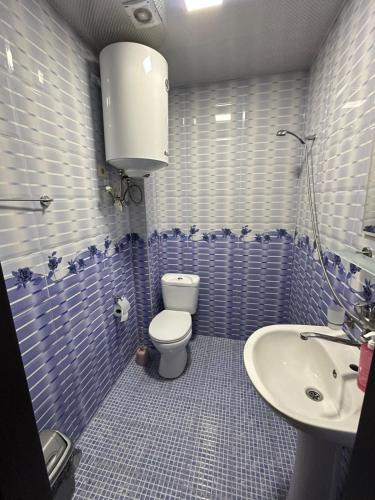 a blue tiled bathroom with a toilet and a sink at Hotel Lile in Ureki