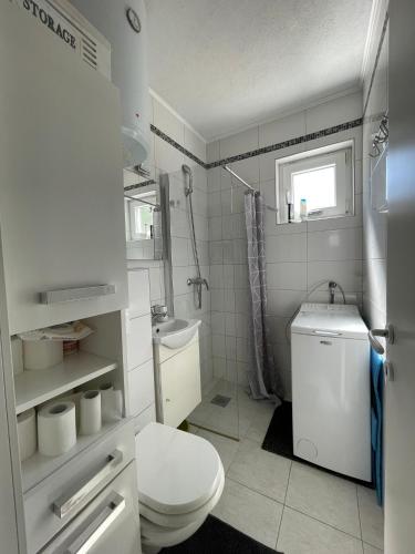 a white bathroom with a toilet and a sink at Seaesta holiday- Modern studio in Okrug Gornji