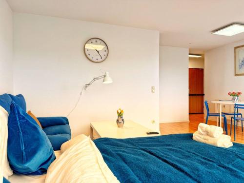 a bedroom with a blue bed and a clock on the wall at Stilvolle Maisonette in Neuss - Balkon & Gratis-Parkplatz in Neuss