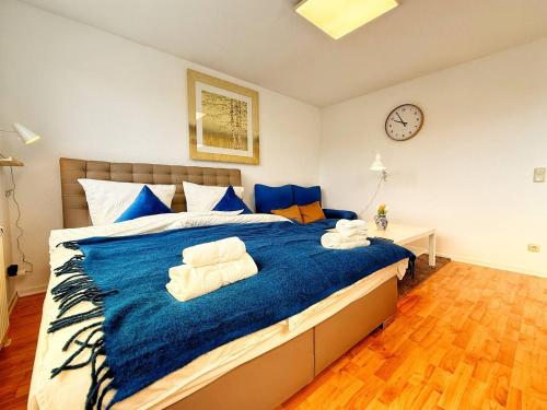 a bedroom with a large bed with blue sheets and a clock at Stilvolle Maisonette in Neuss - Balkon & Gratis-Parkplatz in Neuss