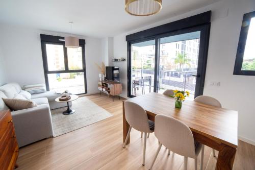 a living room with a wooden table and chairs at Gandia Playa Moderna - nuevo con piscina y parking, 2 banos, playa 300 m, grau 300 m in Playa de Gandia