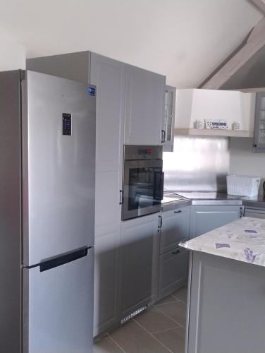 a kitchen with a stainless steel refrigerator and white cabinets at DHofstede vakantiewoning in Oudenaarde