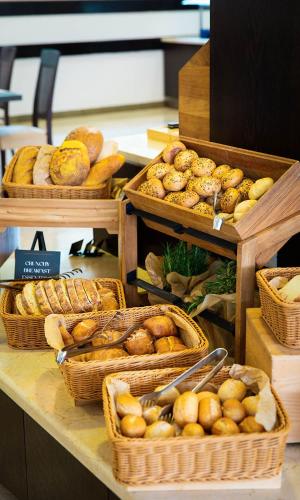 a counter with baskets of bread and baskets of pastries at Aminess Vival Velaris Resort in Supetar