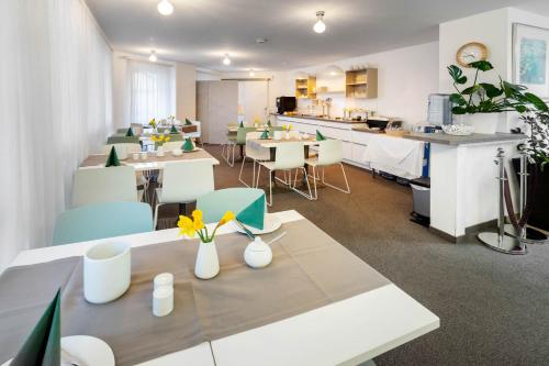 a restaurant with tables and chairs with flowers on them at Appartis - Hotel am Stadtpark in Sindelfingen
