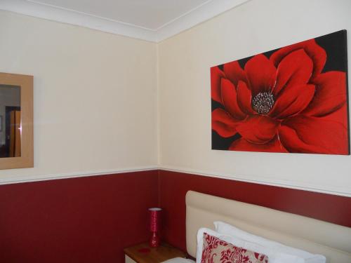 a bedroom with a red flower painting on the wall at All Seasons Guest House in Great Yarmouth