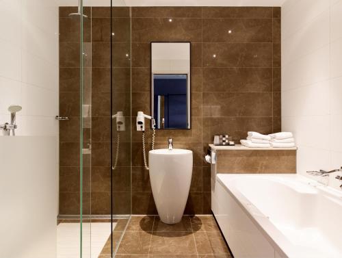 a bathroom with a tub and a sink and a shower at Van der Valk Hotel Den Haag in Nootdorp