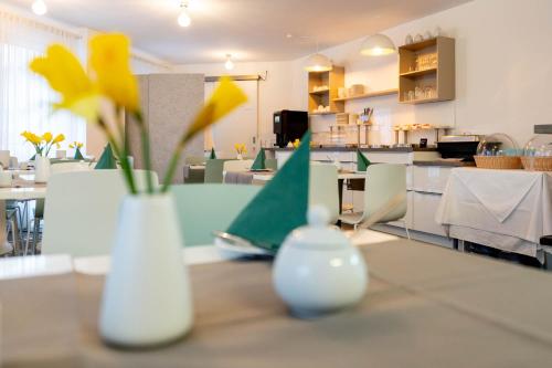 two vases with yellow flowers on a table in a restaurant at Appartis - Hotel am Stadtpark in Sindelfingen