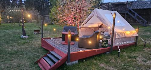 a tent with a wooden deck in a yard at Lighthouse Benki in Užava