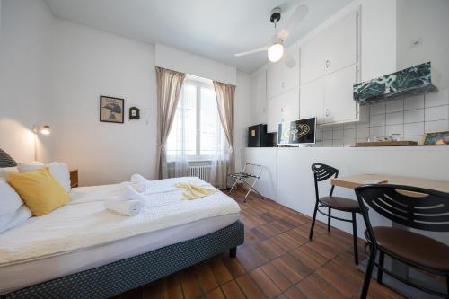 a bedroom with a bed and a table and a kitchen at Rooms Al Festival in Locarno
