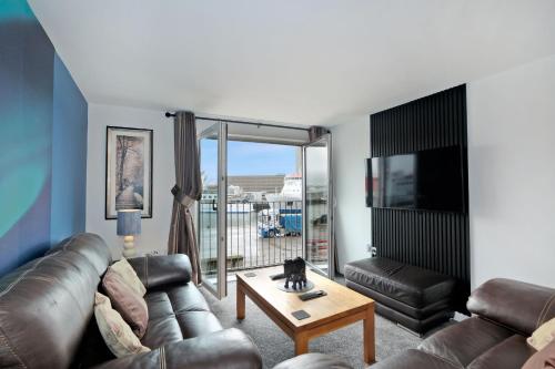 a living room with a leather couch and a table at Luxury 2 Bedroom Harbour Apartment With Panoramic Ship Views in Aberdeen