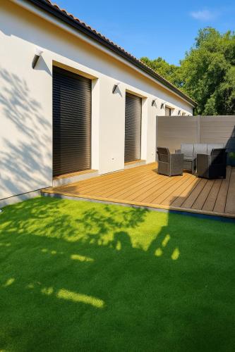 a backyard with a wooden deck and green grass at Évasion balnéo, terrasse, parking, plage - 4 pers in Arès