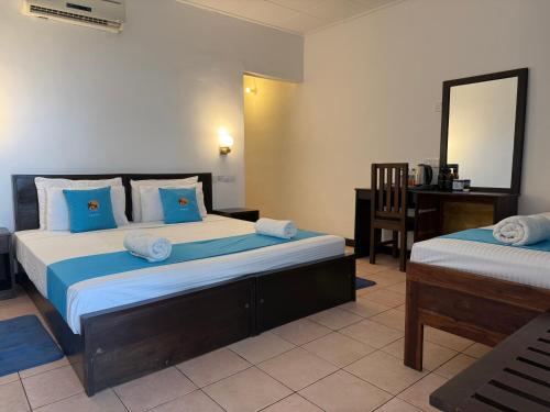 una camera con 2 letti, una scrivania e uno specchio di Hotel Coral Bay a Trincomalee