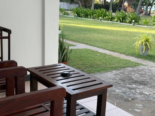 a wooden bench sitting on a porch with a lawn at Hotel Coral Bay in Trincomalee