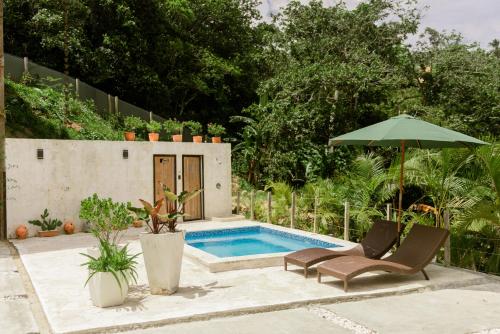 a swimming pool with two chairs and an umbrella at Casa Loma, Descansar en la Montaña, 30min STG in La Búcara