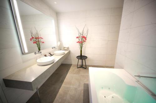 a bathroom with two sinks and a tub and a mirror at Van der Valk Hotel Den Haag in Nootdorp