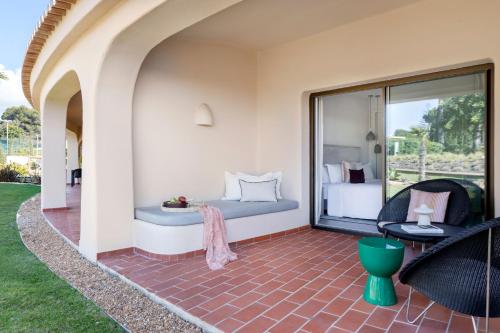 a patio with a bed and a room with a window at Vilalara Grand Hotel Algarve in Armação de Pêra