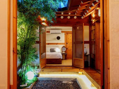 a bedroom in a house with a bed and plants at #오픈할인# 경복궁역 도보 4분#한옥#전통체험#경복궁,인사동,북촌,서촌,광화문,명동, 동대문 바로 옆#짐보관# 9인#호텔침구#각방에어컨#무료와이파이#세탁건조기#교통최고 in Seoul