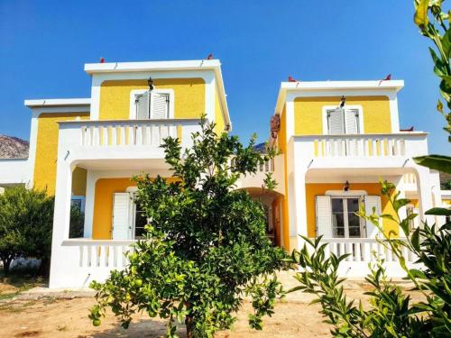a yellow and white house with a tree in front of it at Villa Angeliki II in Kámpos