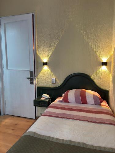 a bedroom with a bed with a headboard and a door at Intimo Hotel Miraflores in Santiago