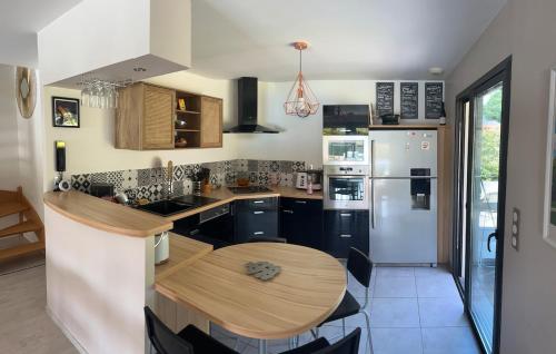 a kitchen with a wooden table and a white refrigerator at Villa paisible à la campagne in Mazerolles