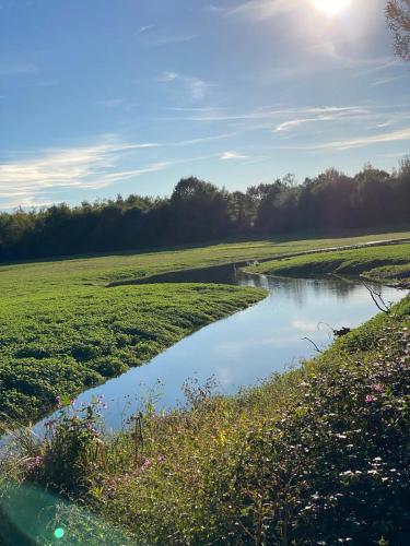 a small river in a field with the sun in the sky at Villa paisible à la campagne in Mazerolles