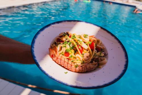 a plate of food on a table next to a pool at Edva Resort in Vlorë