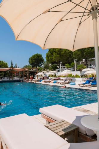 a swimming pool with chairs and an umbrella at Edva Resort in Vlorë