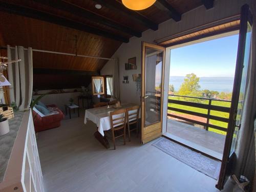 a room with a table and a large sliding glass door at Appartement vue lac in Publier