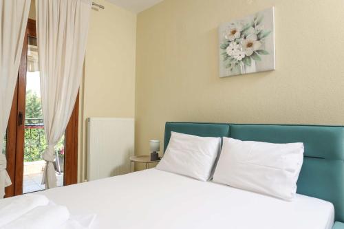 a bedroom with a white bed with a blue headboard at The Blue Horizon House in Afitos