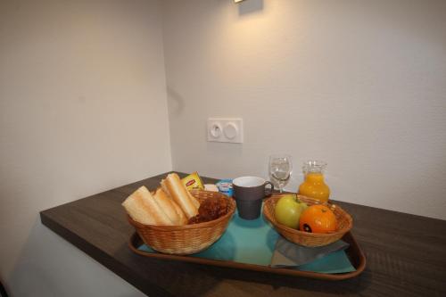 a tray with two baskets of bread and fruit on a table at Logis hôtel restaurant Auberge de la Cloche in Le Theil-sur-Huisne