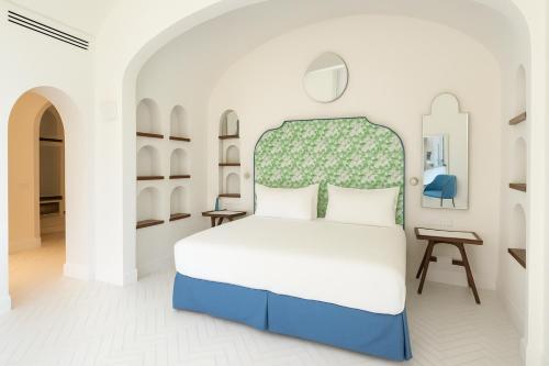 a bedroom with a bed with a green and white headboard at Grand Hotel Europa Palace Sorrento in Sorrento