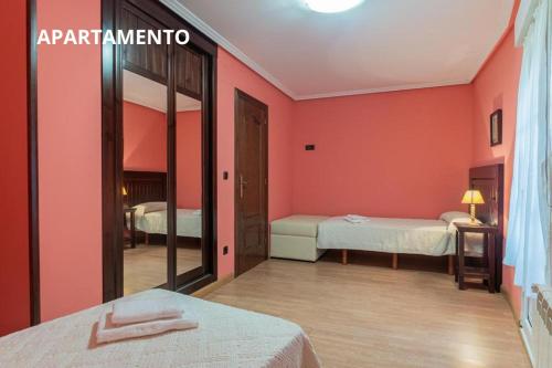 a room with two beds with pink walls at Hotel y Apartamentos La Lonja in Cangas de Onís