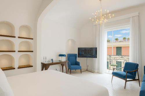 a bedroom with a bed and two chairs and a television at Grand Hotel Europa Palace Sorrento in Sorrento