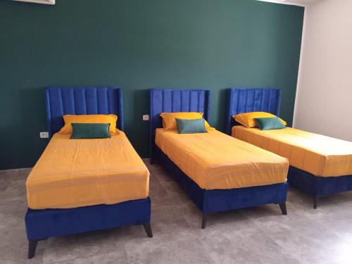 3 Betten in einem Zimmer mit blau und gelb in der Unterkunft Villa Majorelle à Tezdaine in Djerba