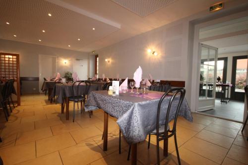 une salle à manger avec des tables et des chaises dans un restaurant dans l'établissement Logis hôtel restaurant Auberge de la Cloche, à Le Theil-sur-Huisne