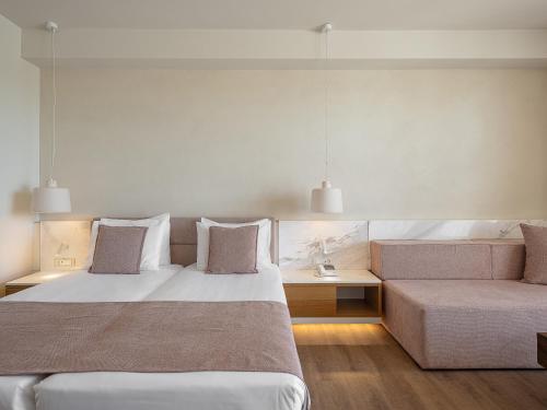 a bedroom with a large bed and a couch at Avra Imperial Hotel in Kolymvari