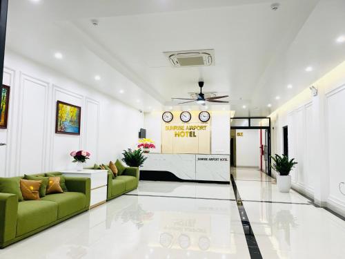 a living room with a green couch and a wall with clocks at Sunrise Airport Hotel - Noi Bai Airport in Thach Loi