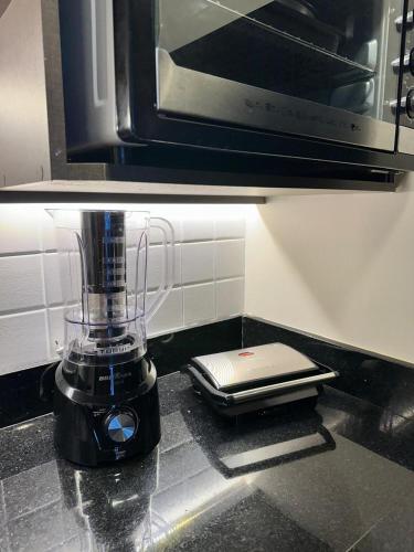 a blender sitting on a kitchen counter with a cell phone at Summit Flat, ótima localização, limpeza diária, academia e piscina in São José dos Campos
