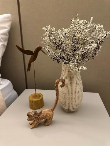 a table with a vase with flowers and a toy animal at Summit Flat, ótima localização, limpeza diária, academia e piscina in São José dos Campos