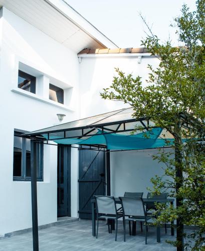d'une terrasse avec une table et des chaises sous un parasol bleu. dans l'établissement OCEAN 53 cottage avec piscine privée, à Lesperon
