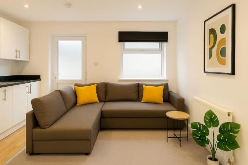 a living room with a brown couch and yellow pillows at 6 Person Apartment in City Centre in Cardiff