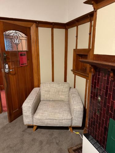 a living room with a chair and a door at Manor on the Park Backpackers in Dunedin