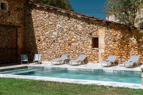 - un groupe de chaises et une piscine à côté d'un bâtiment dans l'établissement Suites de Bruoux, à Gargas