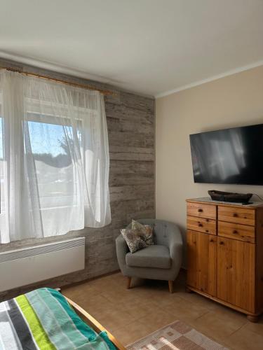 a bedroom with a tv and a chair and a window at Kislőd Apartman in Kislőd