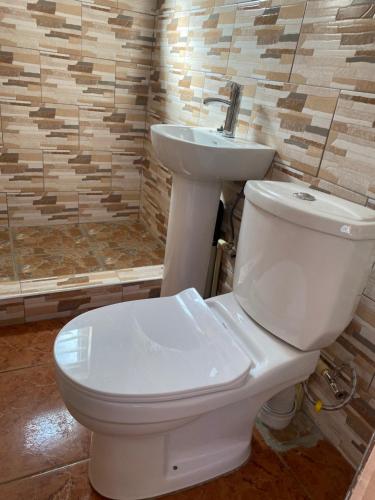 un bagno con servizi igienici bianchi e lavandino. di LaJoy Lodge a Lusaka